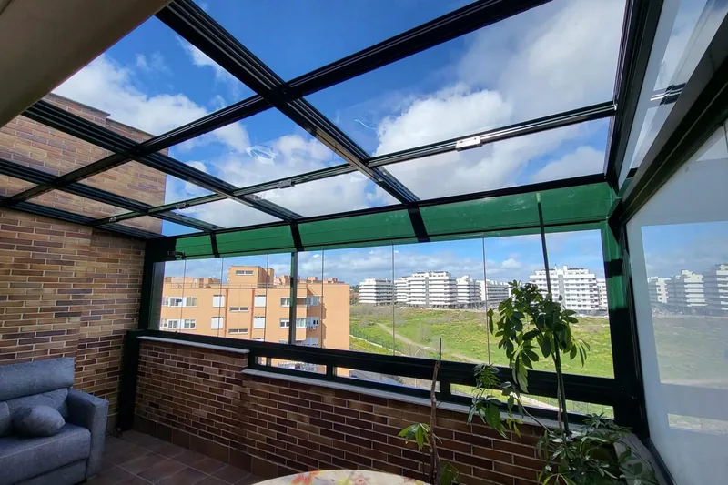 Pérgola bioclimática con lamas orientables abiertas y cortinas laterales de cristal en terraza