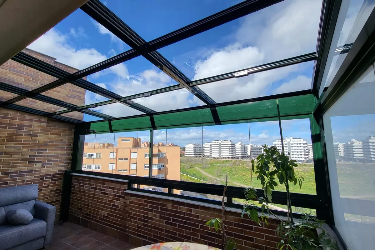 Pérgola bioclimática con lamas orientables abiertas y cortinas laterales de cristal en terraza
