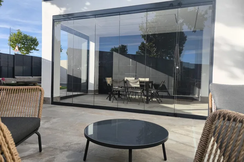 Cerramiento de cristal abatible en porche con vistas a jardín