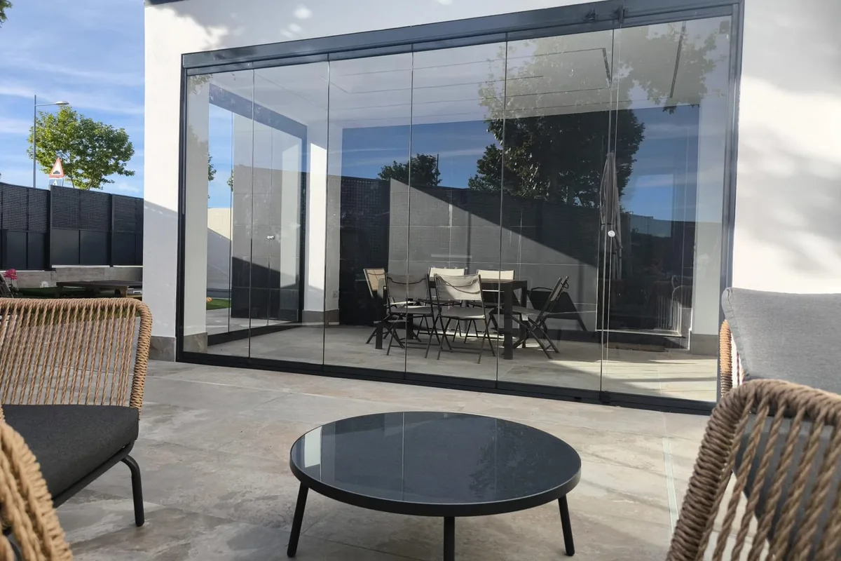 Cerramiento de cristal abatible en porche con vistas a jardín