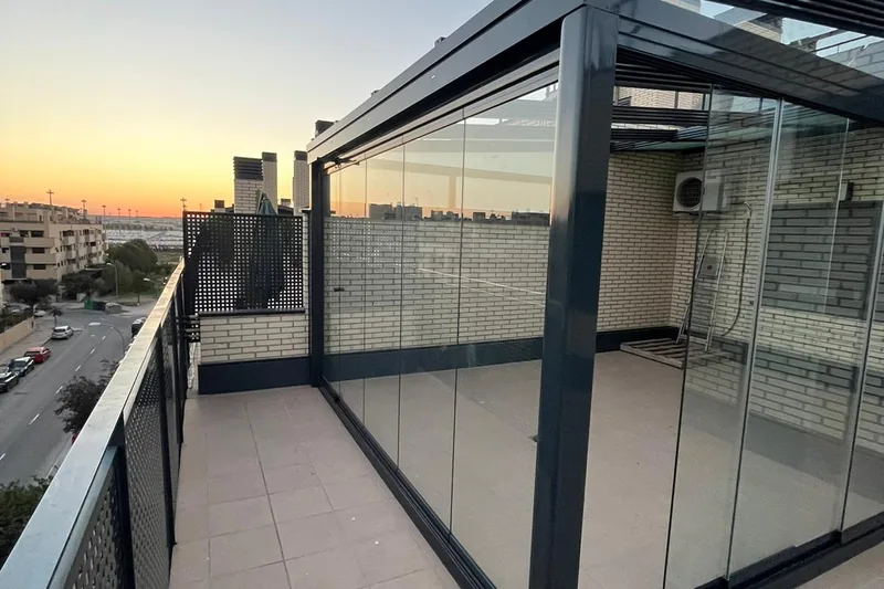 Cortina de cristal corredera en terraza de ático con vistas al atardecer