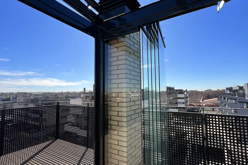 Detalle de las bisagras de una cortina de cristal abatible en un ático