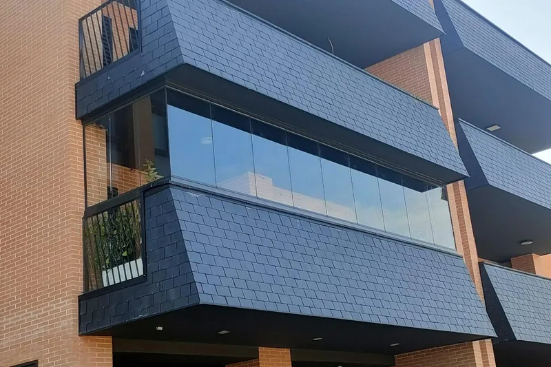 Fachada de edificio con balcón cerrado con cortina de cristal corredera