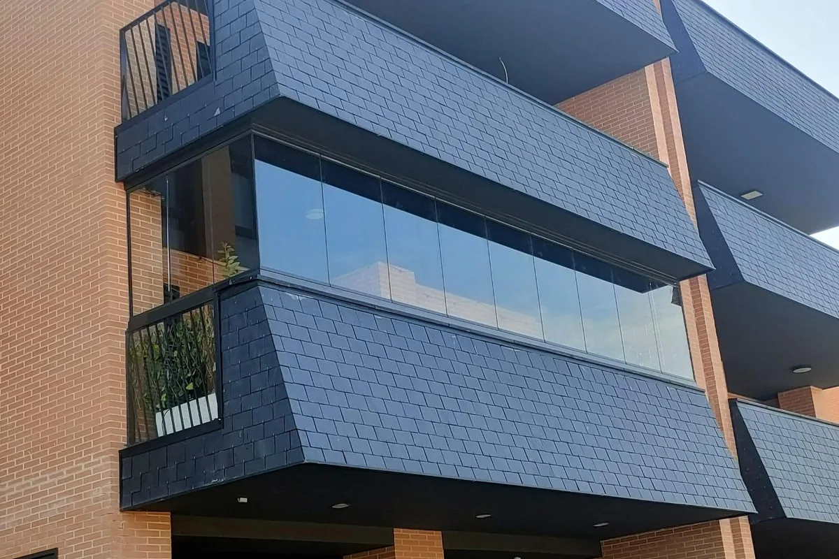 Fachada de edificio con balcón cerrado con cortina de cristal corredera