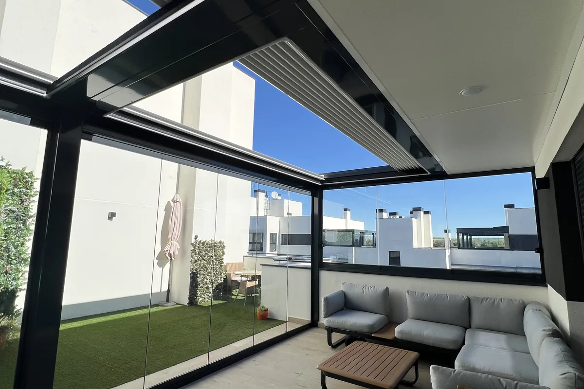 Cerramiento de cristal corredero en porche con sofá y vistas a jardín con césped artificial