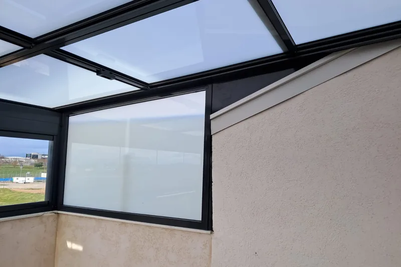 Detalle de techo de cristal fijo con estructura de aluminio junto al alero del edificio