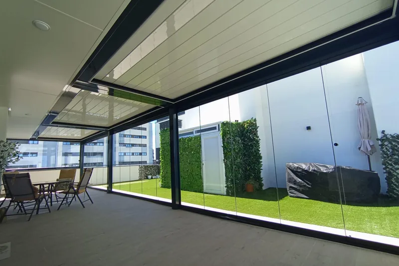 Pérgola bioclimática con cerramiento de cristal y jardín vertical en patio