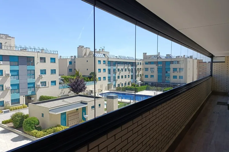 Cerramiento de cristal sin marco en balcón con vistas a piscina comunitaria