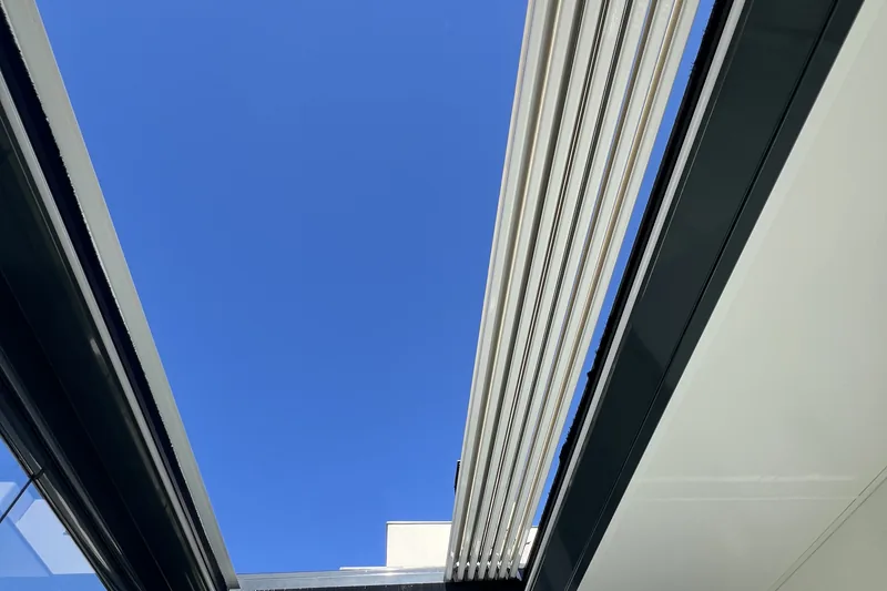 Detalle de pérgola bioclimática con lamas abiertas y estructura de aluminio en negro