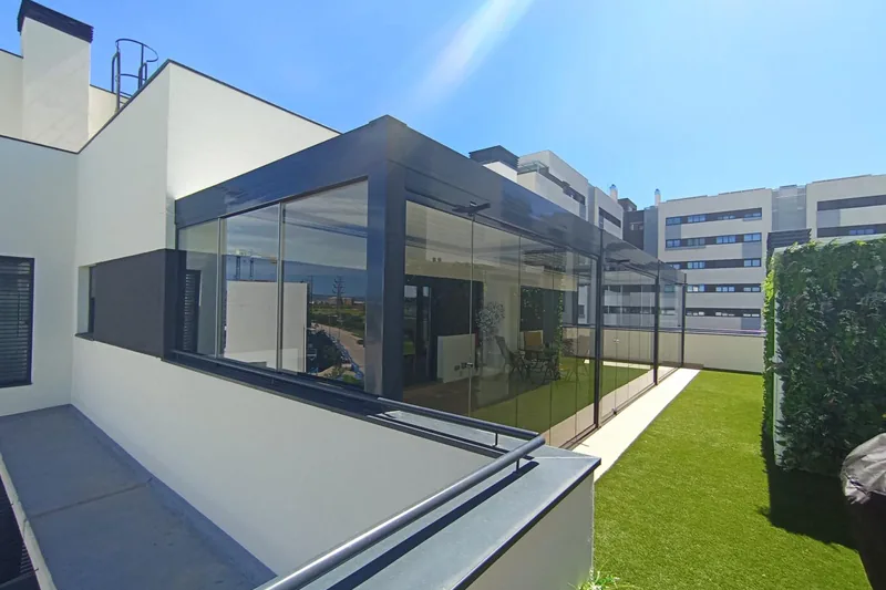 Ampliacion de vivienda con cortina de cristal corredera y jardín con césped artificial