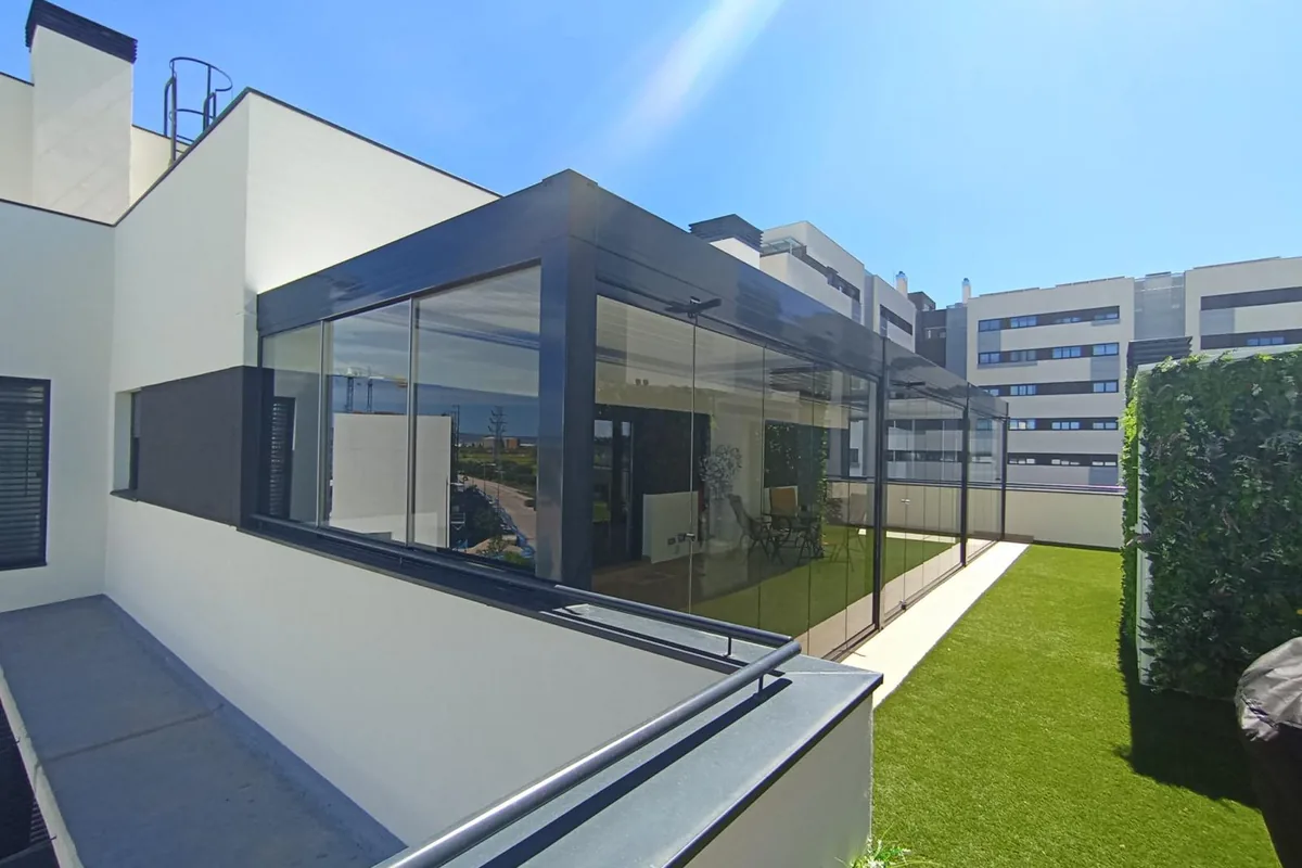 Ampliacion de vivienda con cortina de cristal corredera y jardín con césped artificial