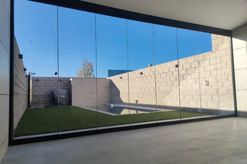 Cerramiento de cristal panorámico en terraza con vistas a jardín y piscina