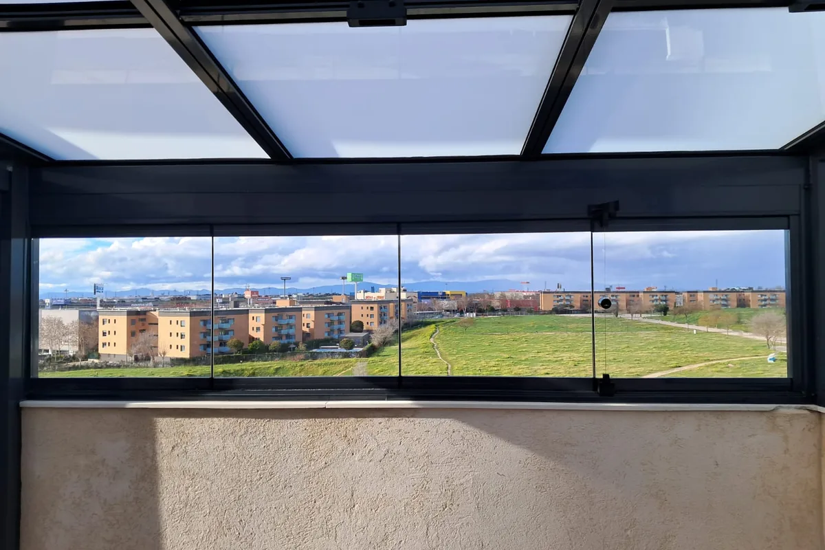 Terraza acristalada con techo de cristal fijo y vistas panorámicas a la ciudad