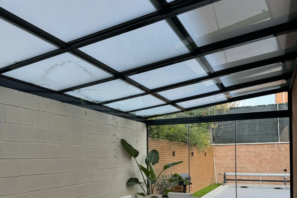 Techo de cristal con perfilería negra sobre el patio de una vivienda de Madrid