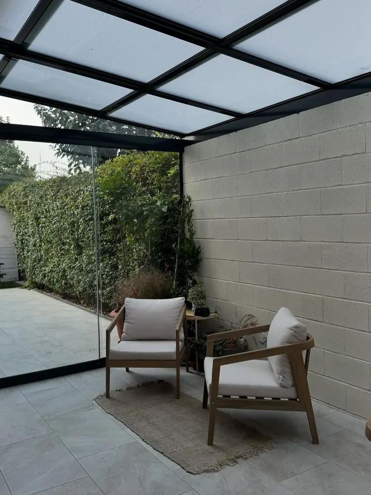 Rincón de estar bajo el techo acristalado del patio de una vivienda de Madrid