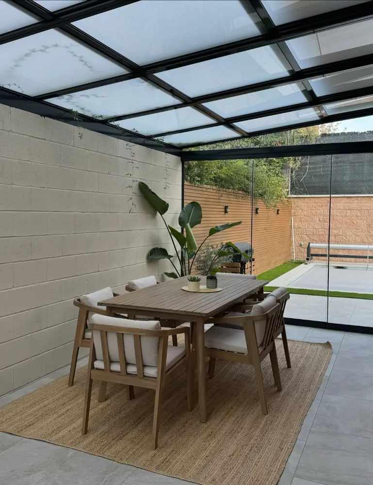 Comedor bajo el techo de cristal instalado en el patio de una vivienda de Madrid