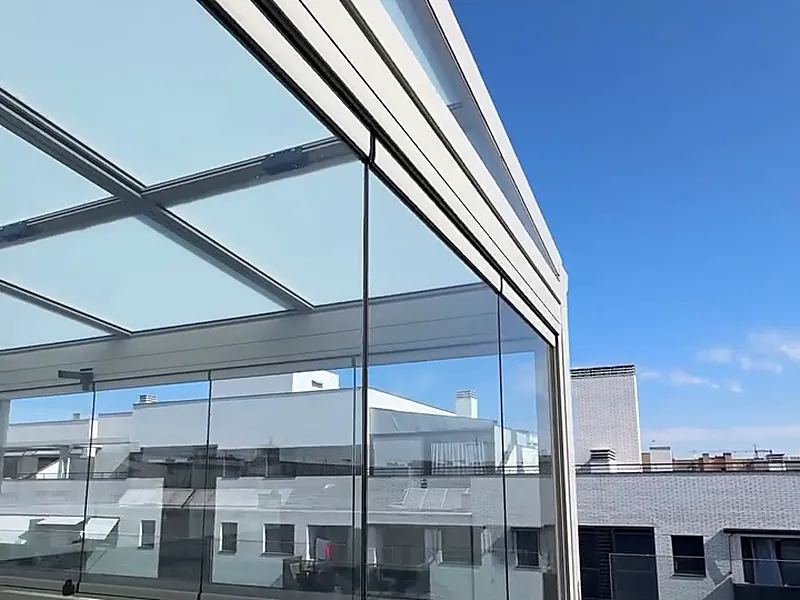Terraza de un ático de Madrid cerrada con cortinas de cristal correderas, vista desde fuera sobre los tejados