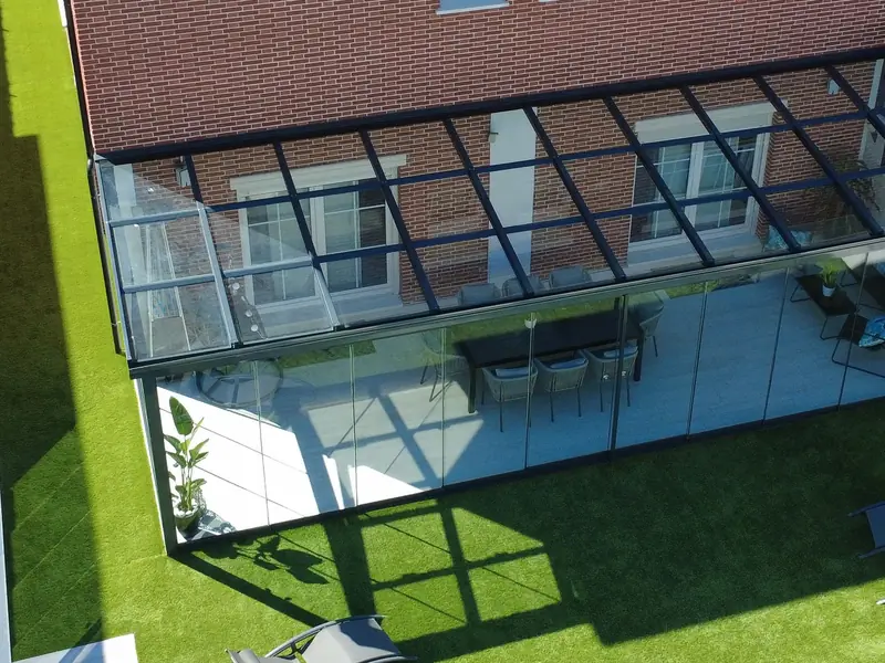 Vista aérea de un patio cerrado con cortinas de cristal correderas y techo de cristal en una vivienda de Madrid