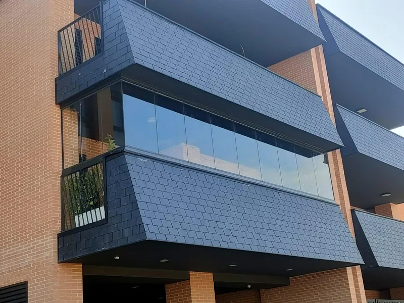 Fachada de un edificio de Madrid con varios balcones cerrados con cortinas de cristal