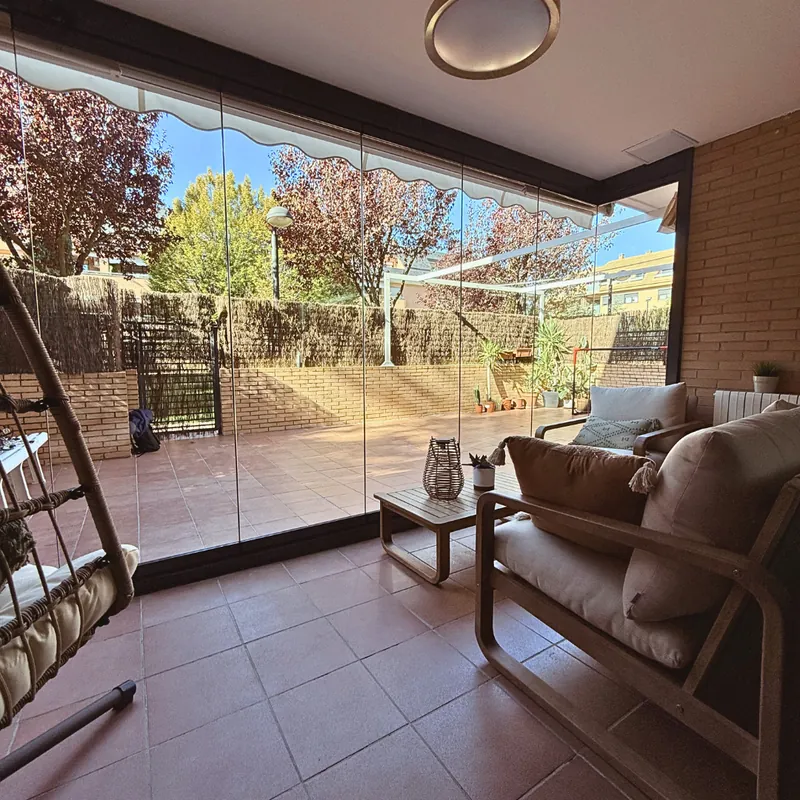Porche convertido en salón exterior con cortinas de cristal en Madrid