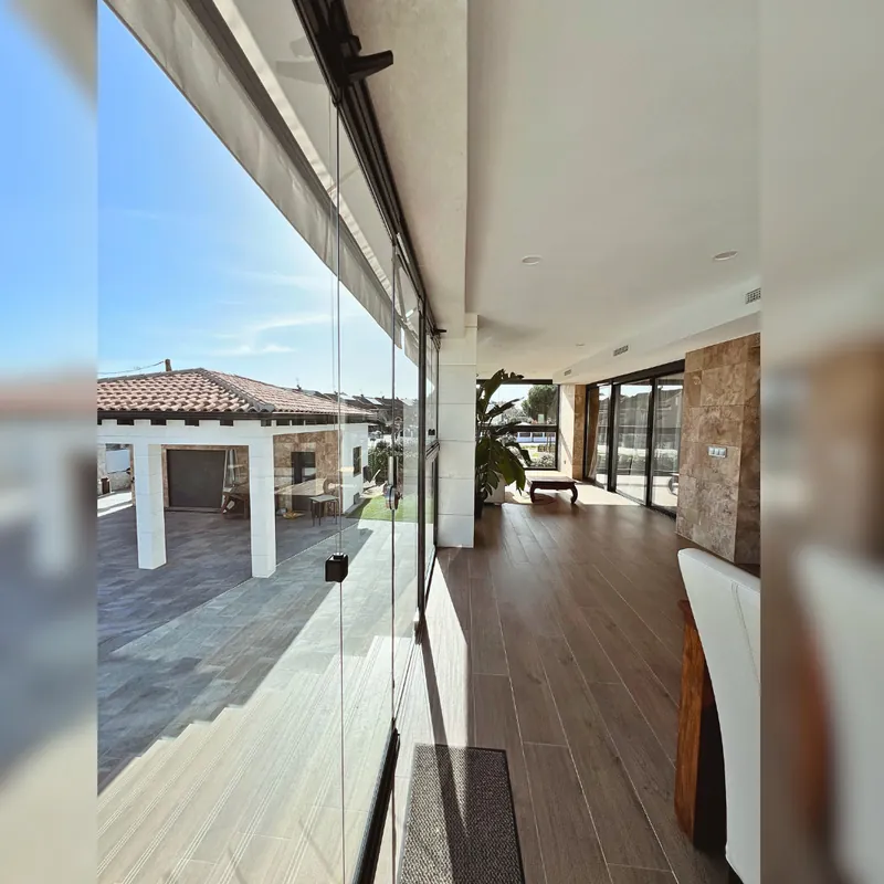 Porche con tarima cerrado con cortinas de cristal en una vivienda de Madrid