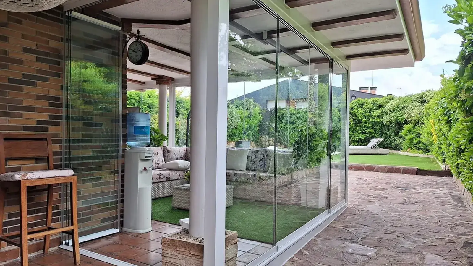 Porche de un chalet de Madrid cerrado con cortinas de cristal frente al jardín