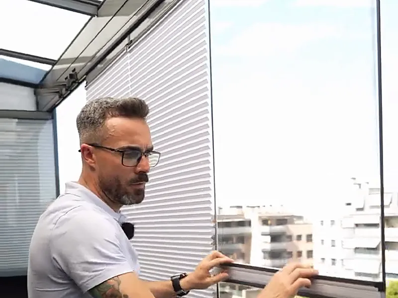 Estor montado sobre una hoja de cortina de cristal en una terraza de Madrid