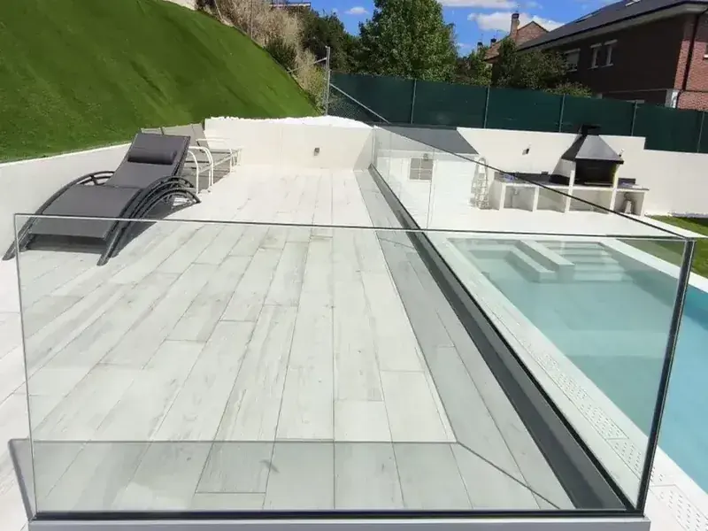 Barandilla de cristal sin montantes junto a la piscina de un chalet en Madrid