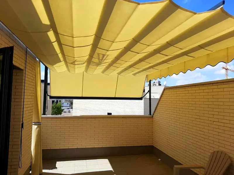 Toldo veranda desplegado sobre una terraza con paredes de ladrillo en Madrid