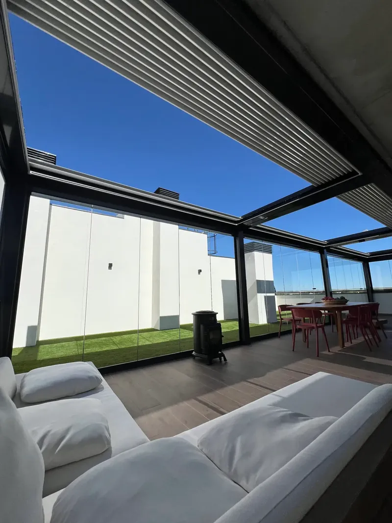 Pérgola bioclimática combinada con cortinas de cristal en una terraza de Madrid