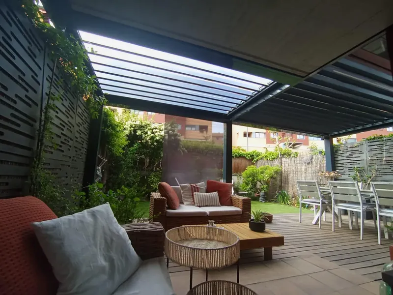 Pérgola bioclimática de lamas orientables sobre la zona de estar del jardín de un chalet en Madrid