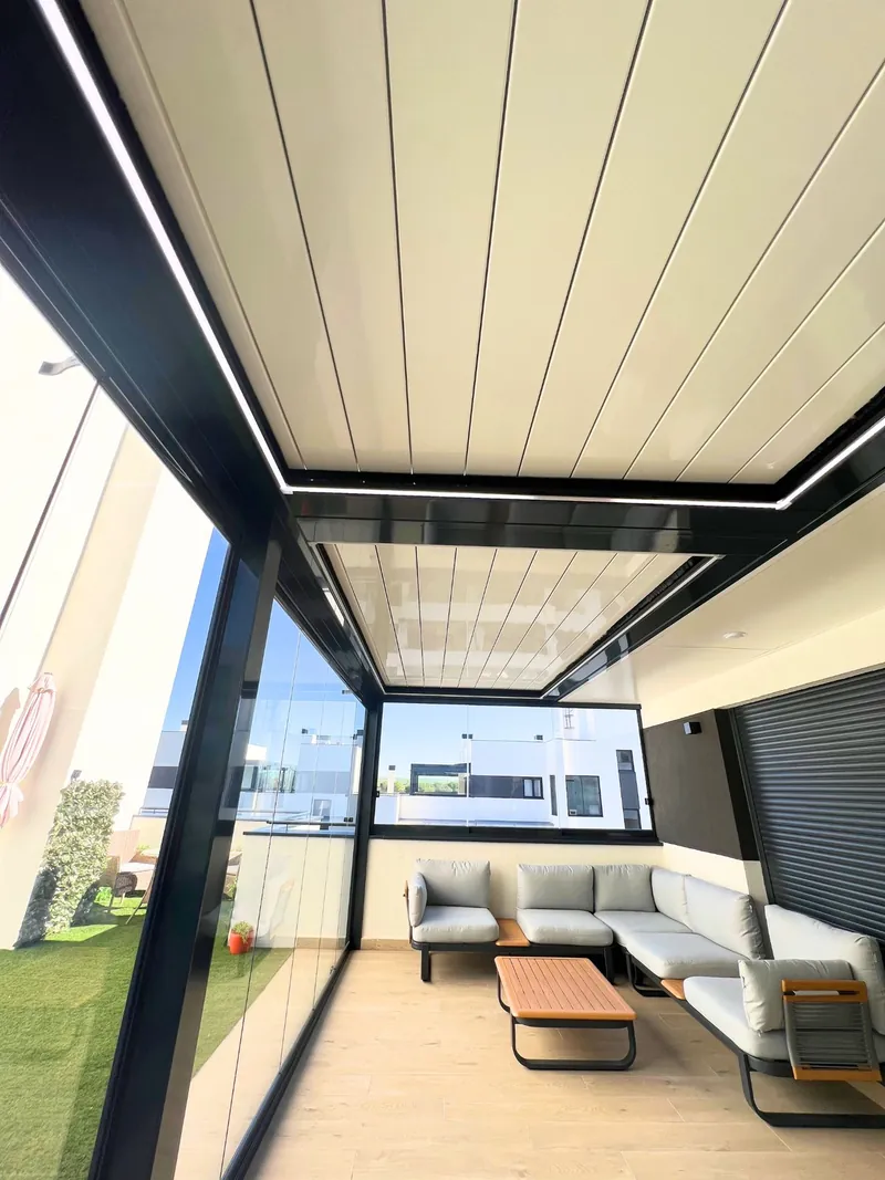 Pérgola bioclimática de lamas beige sobre un salón exterior en Madrid