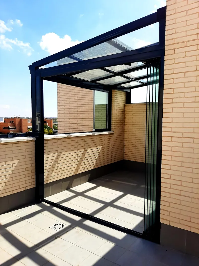 Techo de cristal apoyado en una fachada de ladrillo en una terraza de Madrid