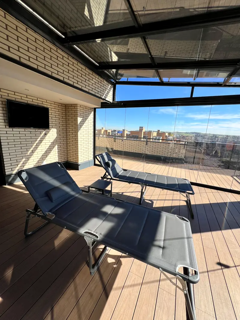 Techo de cristal fijo con parasol integrado y panel perforado de privacidad en terraza de atico