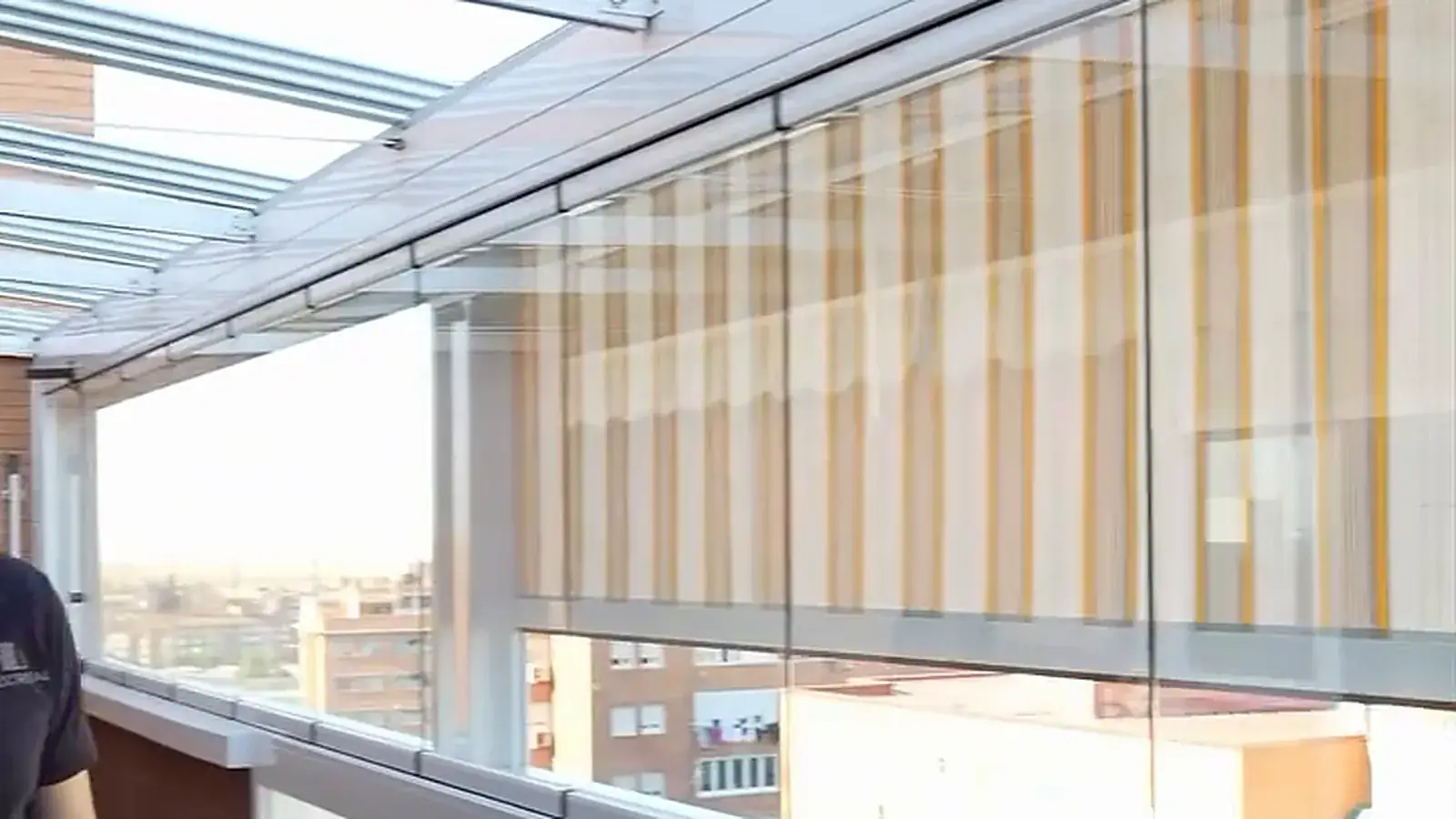 Toldo vertical de lona bajado junto al cristal de una terraza acristalada en Madrid
