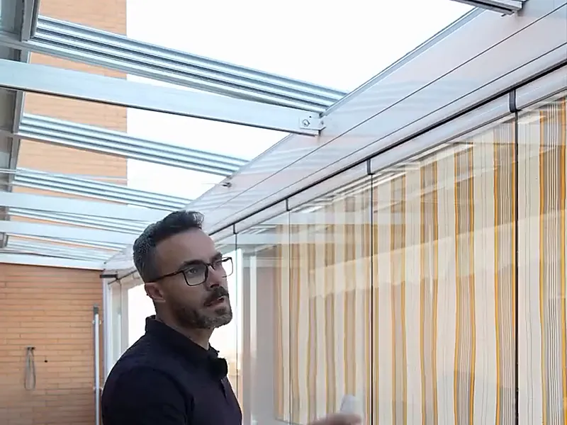 Toldo vertical con guías instalado en la terraza acristalada de un ático de Madrid